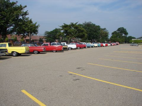 1992 Ford Taurus - A variety of classic vehicles are parked in rows in an outdoor lot under a partly cloudy sky.