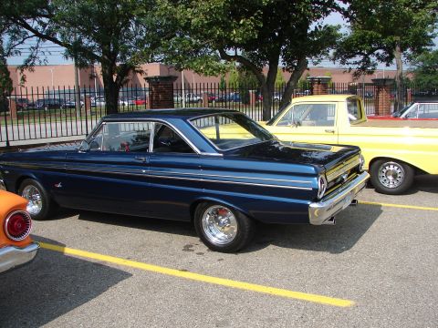 1992 Ford Taurus - A dark blue 1964 Ford Falcon coupe is parked next to a yellow pickup truck at an outdoor event.