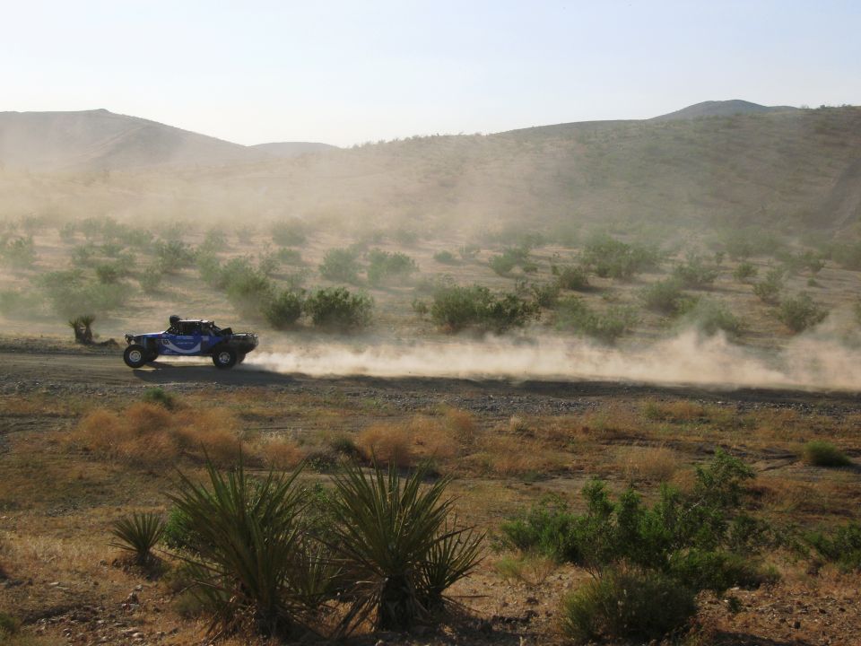 Blue off-road buggy racing on dusty desert road