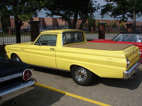 1992 Ford Taurus - A yellow 1960 Ford Falcon Ranchero pickup truck is parked next to another vehicle.