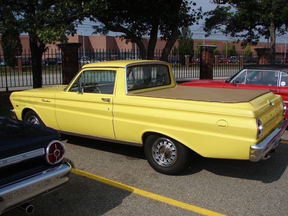 Yellow 1960 Ford Falcon Ranchero pickup truck parked next to a red car