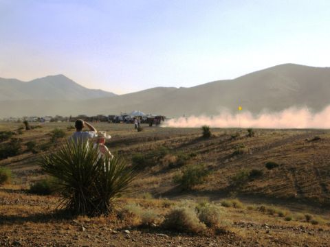 1986 Ford Bronco - Dust billows from vehicles participating in a desert race, observed by spectators.