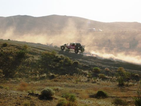 1986 Ford Bronco - A buggy races across a dry, hilly terrain, leaving a trail of dust in its wake.