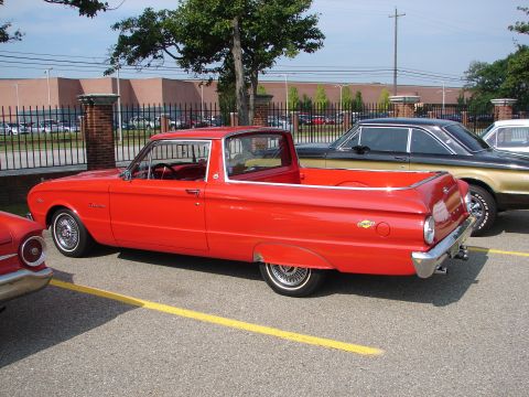 1992 Ford Taurus - A red 1960 Ford Falcon Ranchero pickup truck is parked next to other vehicles.