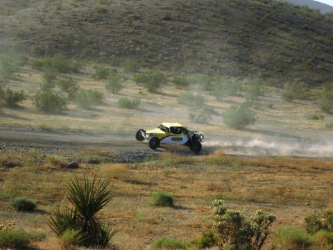 1986 Ford Bronco - An off-road buggy races across a dusty desert terrain, its tires leaving a trail of dust in its wake.