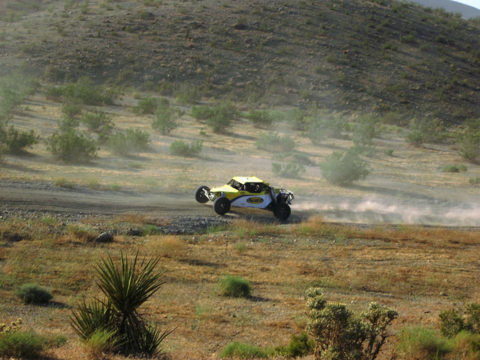 Yellow and white off-road buggy kicking up dust on a dirt track
