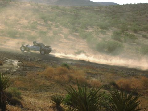 1986 Ford Bronco - A modified off-road truck races across a dusty, arid landscape.