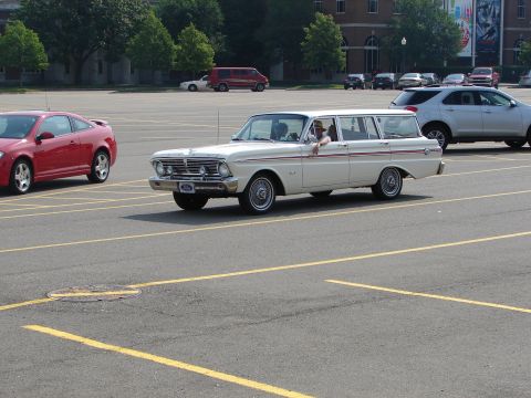 1992 Ford Taurus - A classic white station wagon drives through a parking lot with other vehicles present.