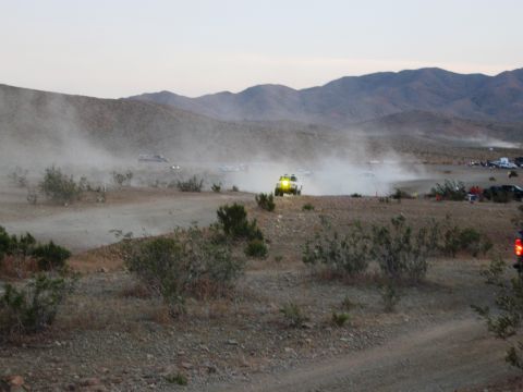 1986 Ford Bronco - Vehicles race across a dusty desert landscape under a hazy sky with mountains in the distance.