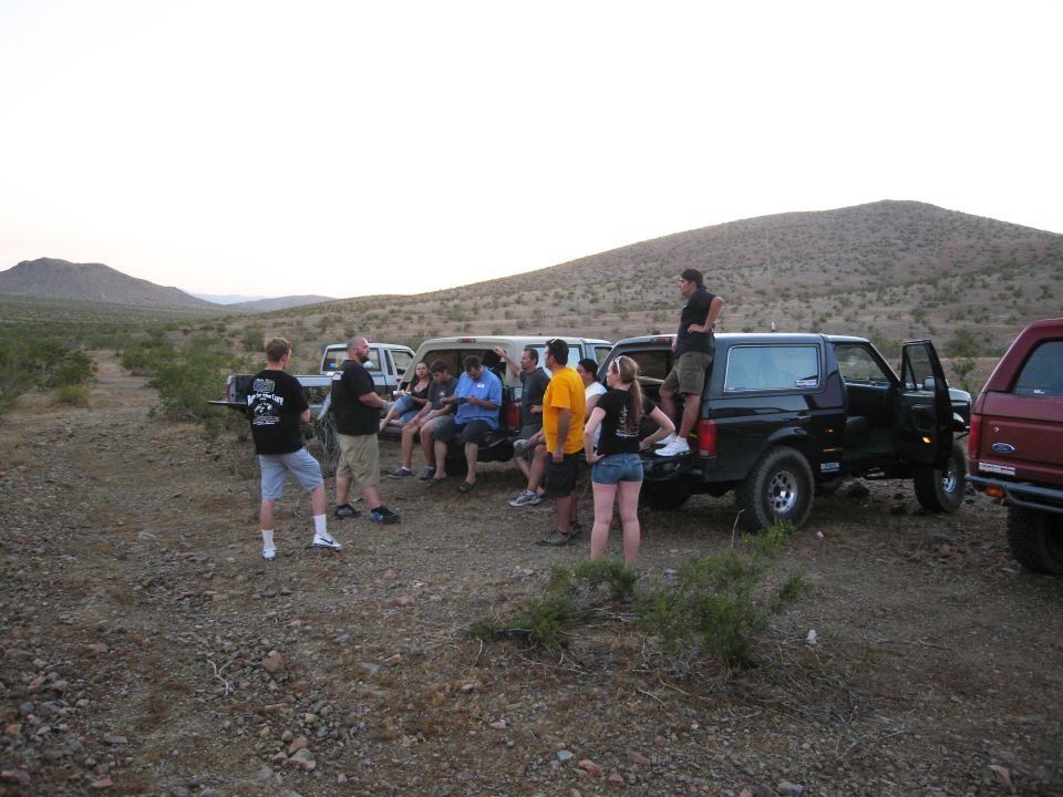 Black Ford Bronco with doors open, parked in desert with people around