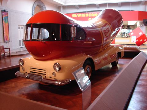 1992 Ford Taurus - The iconic Oscar Mayer Wienermobile is displayed indoors, its distinctive hot dog-shaped body on a vintage chassis.