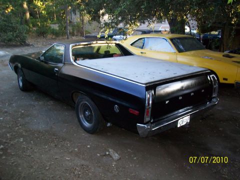 1972 Ford Ranchero - Rear view of a black 1972 Ford Ranchero pickup, a white tonneau cover and a yellow car parked behind it.