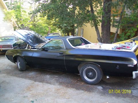 1972 Ford Ranchero - A black 1972 Ford Ranchero is parked outside with its hood open, next to another vehicle.