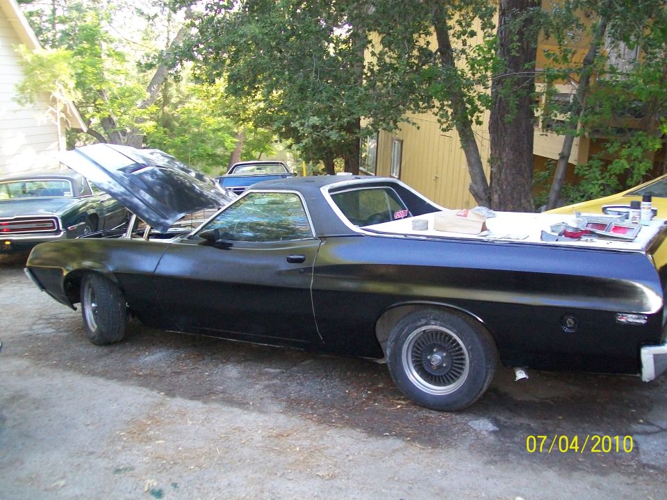 Ford Ranchero in fresh black paint with hood open, driver-side profile during restoration