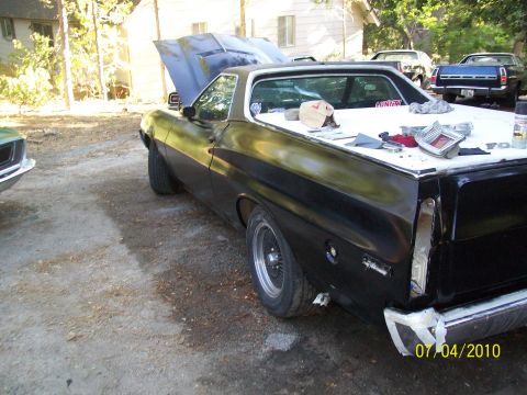 1972 Ford Ranchero - This black Ford Ranchero appears to be from the early 1970s, possibly a 1970 model, with its hood up and parts laid out on the bed.