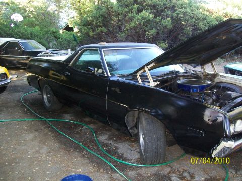 1972 Ford Ranchero - A black 1972 Ford Ranchero is parked with its hood open, revealing the engine. Another vehicle is partially visible in the background.