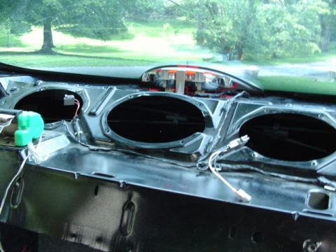 1999 Ford Taurus - The dashboard of a car is shown with the speaker grilles removed, revealing the interior components and wiring.