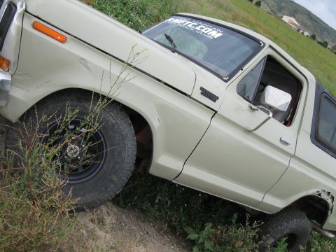 1978 Ford Bronco - This 1978 Ford Bronco is captured in a three-quarter front view, navigating an off-road trail with tires.
