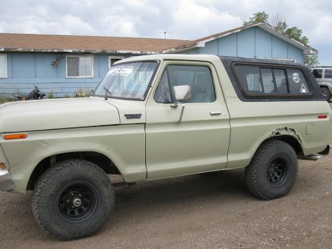 1978 Ford Bronco - Side view of a 1978 Ford Bronco with a black removable hardtop and visible rust damage.