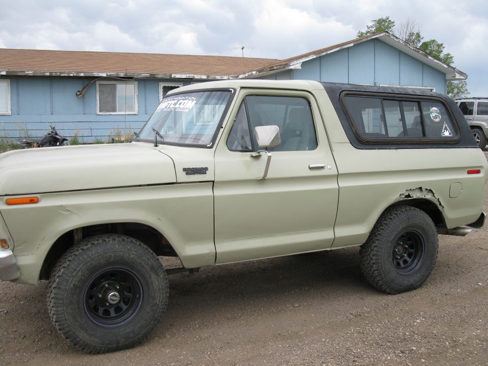 1978 Ford Bronco, tan with black top, showing rust on rear fender