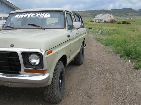 1978 Ford Bronco - A light green 1978 Ford Bronco is parked on a dirt road with a house in the background.