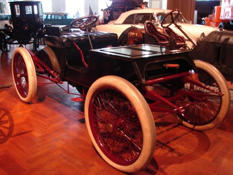1992 Ford Taurus - An early automobile with a black body, red frame, and white tires is displayed indoors.