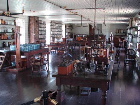 1992 Ford Taurus - A historical laboratory scene displays numerous glass beakers, bottles, and scientific apparatus on wooden tables and shelves.