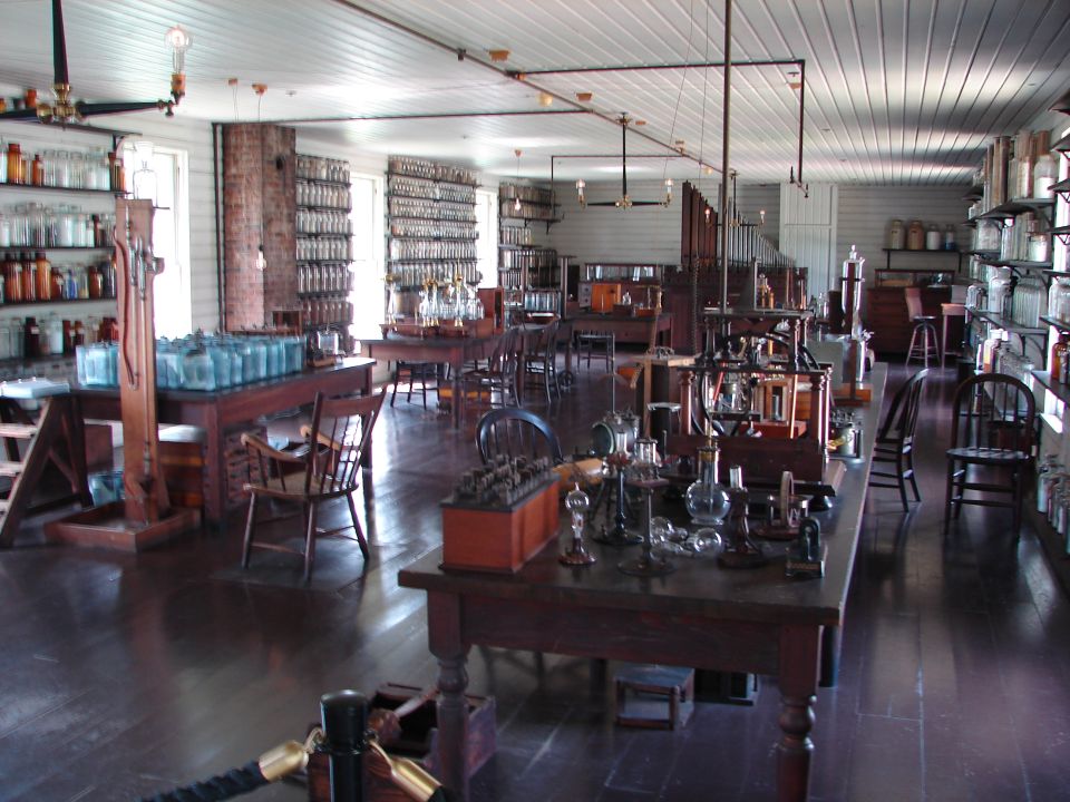 Laboratory with shelves of bottles and scientific equipment on wooden tables