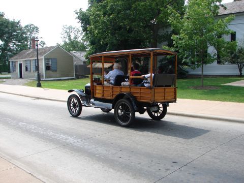 1992 Ford Taurus - This antique wooden wagon with a canopy top is seen driving down a street with passengers inside.