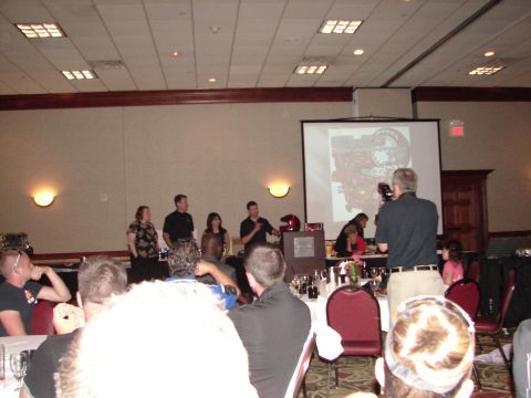 1992 Ford Taurus - Attendees watch a presentation during a convention, with a projector displaying an engine schematic on a large screen.