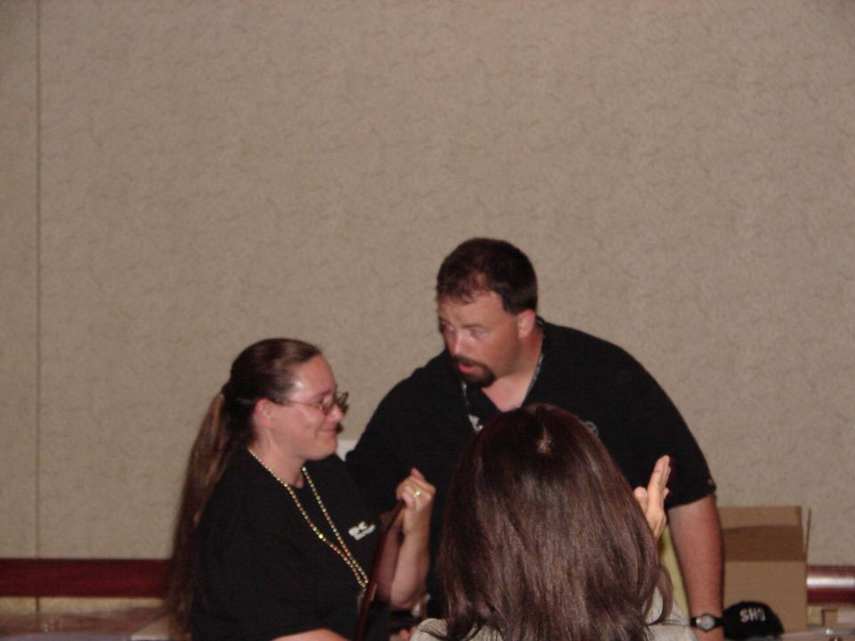 People talking at a convention, with a Supermotors logo visible