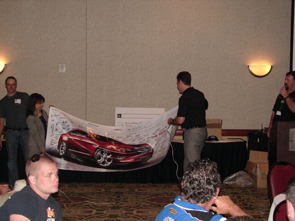 Red car depicted on a banner with signatures, held by people