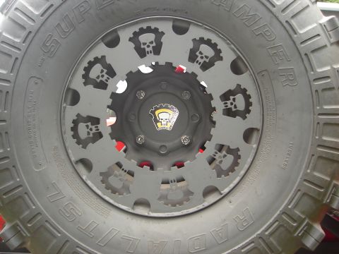 1989 Ford Bronco - This custom wheel features a unique design with skull and gear cutouts, mounted on a large off-road tire.
