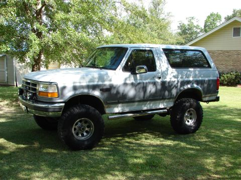1995 Ford Bronco - This lifted Ford Bronco has a two-tone paint scheme and is parked outdoors on a sunny day.