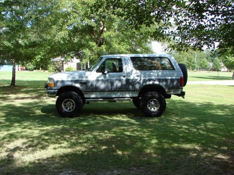 1995 Ford Bronco - This lifted 1995 Ford Bronco is parked on a grassy lawn under the shade of trees.