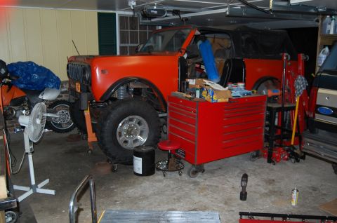 1994 Ford Bronco - Orange International Scout II in a garage, undergoing work. A motorcycle is parked nearby.