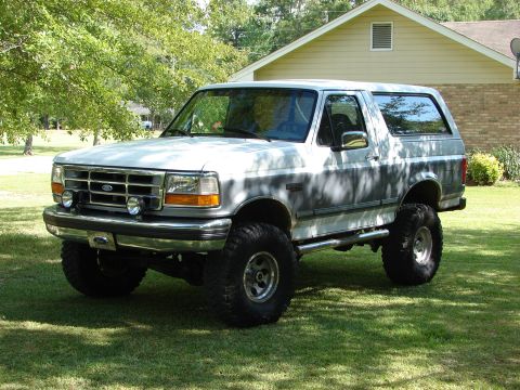1995 Ford Bronco - This lifted 1995 Ford Bronco is parked on a grassy lawn in front of a house.