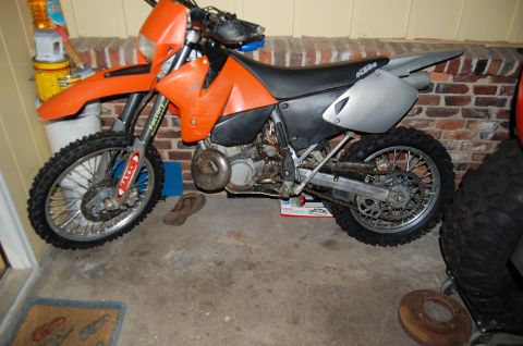 1994 Ford Bronco - An orange dirt bike is parked indoors next to a brick wall.