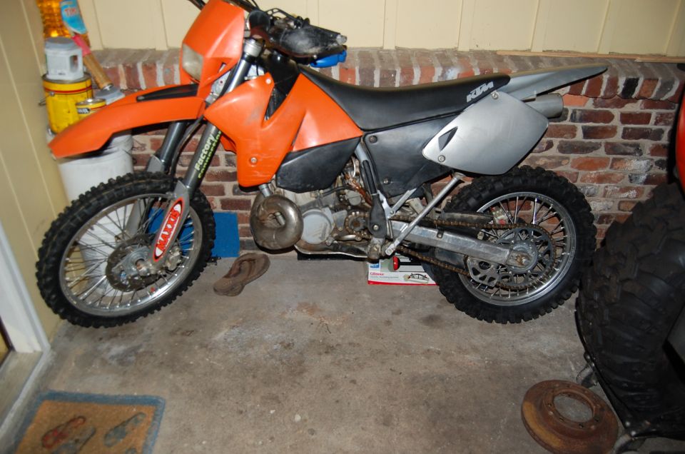 Orange dirt bike with black seat and silver side panels, parked indoors