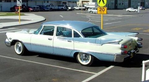1991 Ford Crown Victoria - A vintage two-tone sedan with prominent tail fins is parked in an outdoor lot.