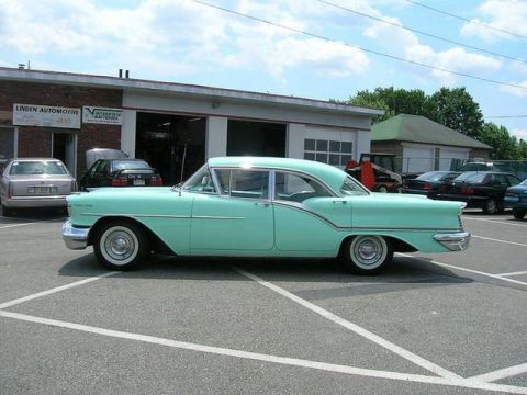 1991 Ford Crown Victoria - A vintage mint green Oldsmobile 88 is parked in front of an auto repair shop.