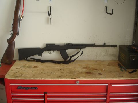 1989 Ford Bronco - A workbench displays two firearms and a metal ammunition can, with a red tool chest below.