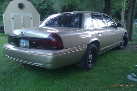 2000 Mercury Grand Marquis - The rear of a gold Mercury Grand Marquis is shown parked on a grassy lawn next to a shed.