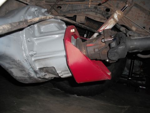1991 Ford Bronco - Close-up view of a vehicle's rear differential, a red skid plate and driveshaft.