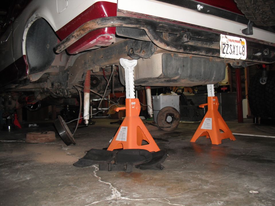 Undercarriage of a 1991 Ford Bronco on jack stands, showing fuel tank and suspension