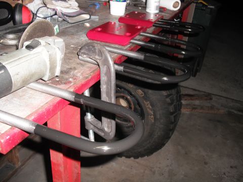 1991 Ford Bronco - Workshop scene with automotive parts and tools, including an angle grinder and leaf springs.