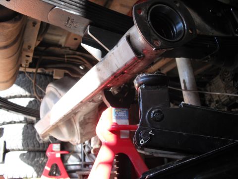 1991 Ford Bronco - The underside of a 1991 Ford Bronco is visible, supported by jack stands, with components like leaf springs and the differential in view.