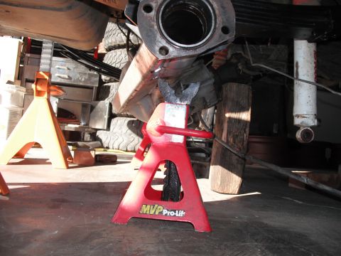1991 Ford Bronco - Vehicle undercarriage supported by jack stands, with focus on the exhaust system and suspension components.