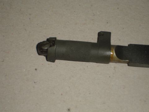 1989 Ford Bronco - A close-up view of a metal part with a textured grip and a pivoting mechanism, likely a component of a weapon.