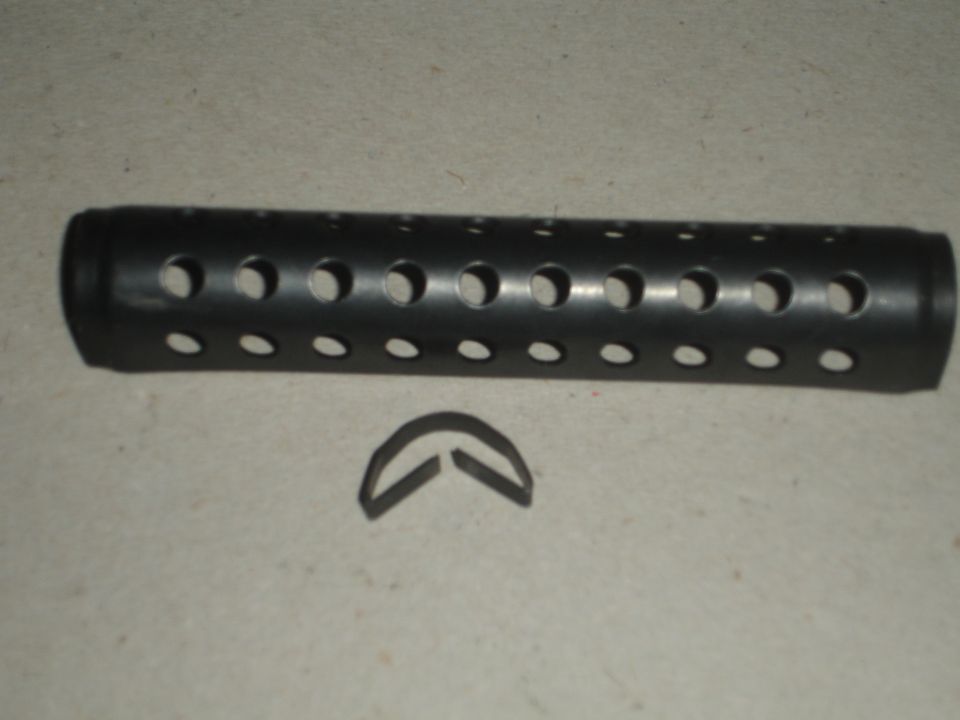 Black perforated exhaust tip and metal clip on a textured surface